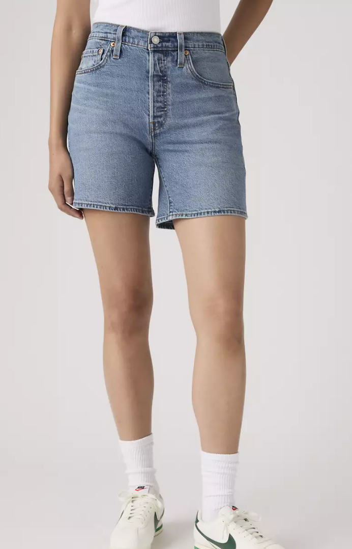 Person wearing Levi's light blue denim shorts on a white background