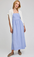 Woman wearing a blue striped dress with a white cardigan on a gray background