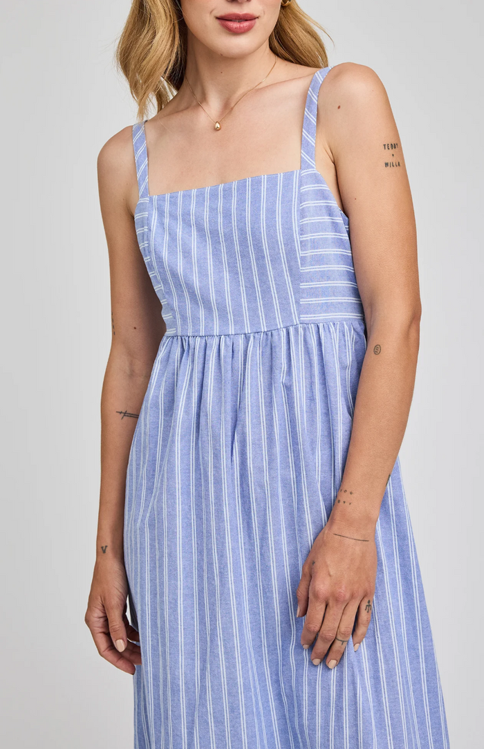 Woman wearing a blue and white striped dress against a plain background