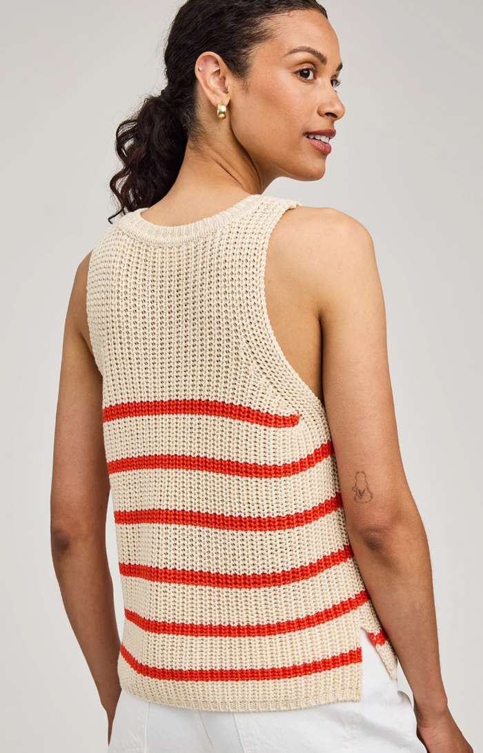 Woman wearing a beige sleeveless knitted top with grenadine stripes on a plain background