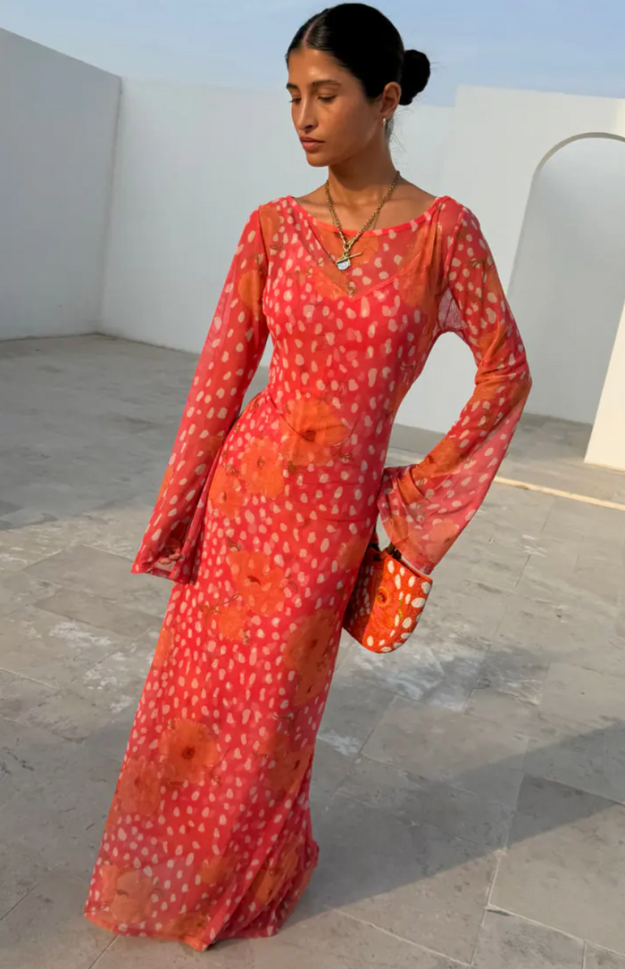 Woman wearing a red and orange patterned dress in an outdoor setting.
