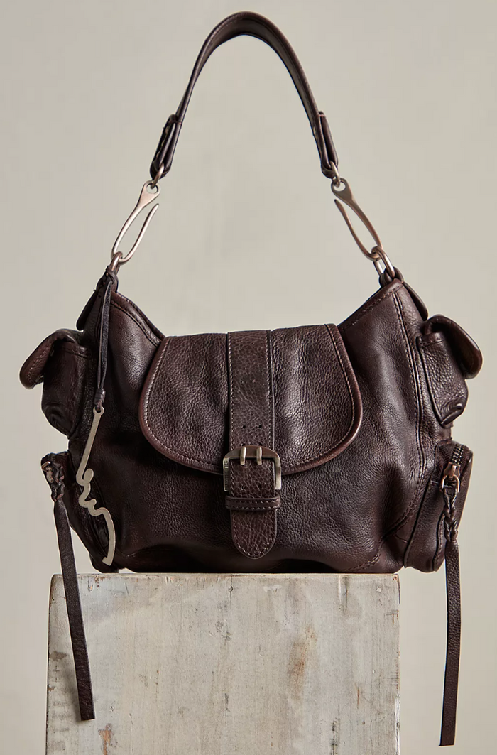 Brown leather handbag on a light wooden surface with a neutral background