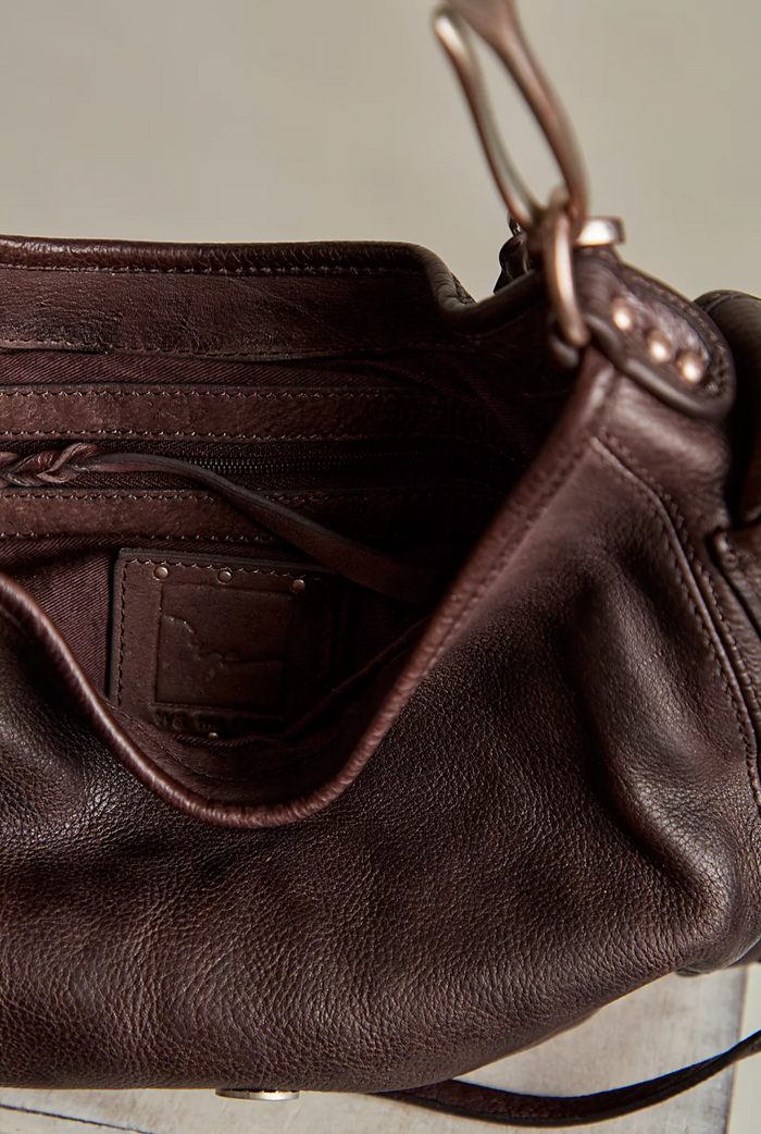 Close-up of a brown leather handbag with a visible brand logo.