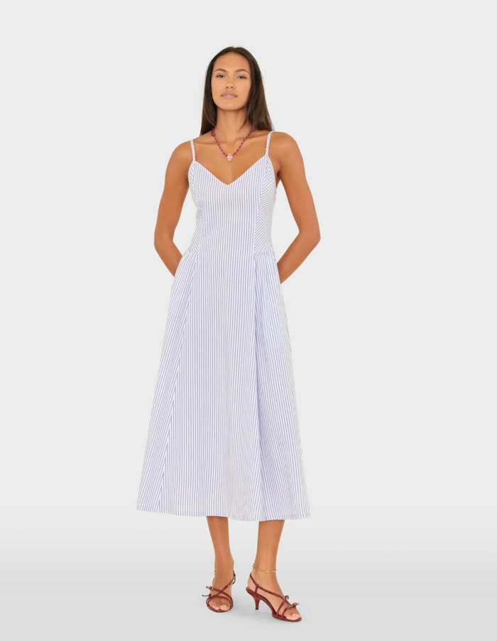Woman wearing a white dress with blue stripes on a plain background