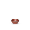 A tiny rounded ceramic bowl in a cool burnt terracotta color featuring iron speckles and an unglazed rim