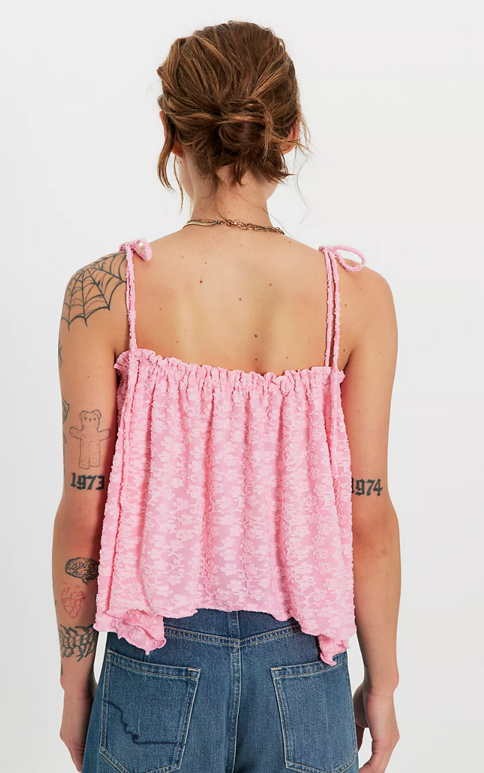 Person wearing a flower lace top and blue jeans on a white background, back view