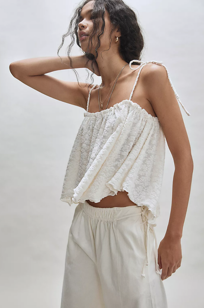 Woman wearing a sugar ruffled top and pants on a plain background