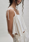 Woman wearing a sugar lace top with thin straps on a plain background, side view