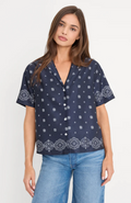 Woman wearing a navy blue patterned shirt with short sleeves on a white background