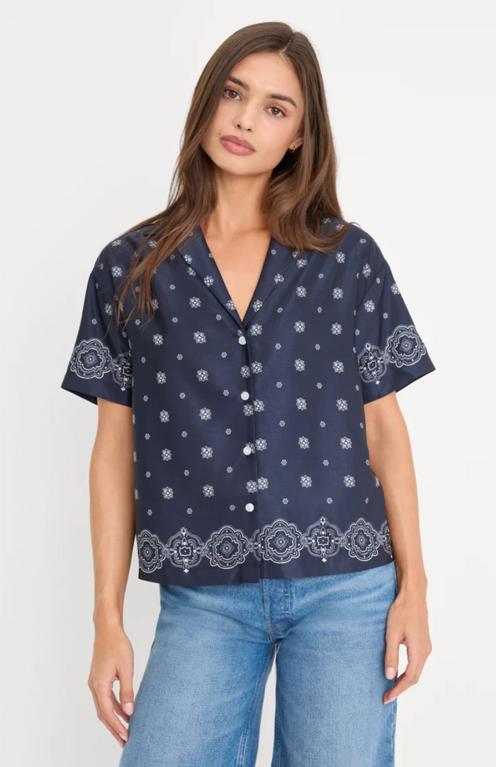 Woman wearing a navy blue patterned shirt with short sleeves on a white background