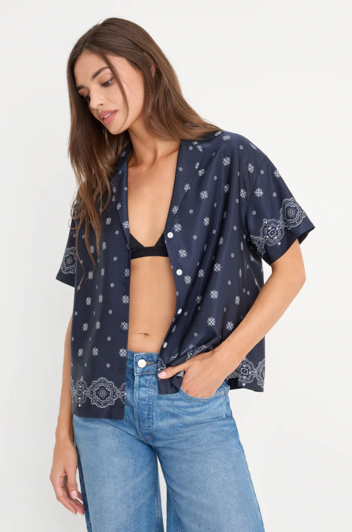 Woman wearing a navy patterned kimono over a black bralette and blue jeans on a white background