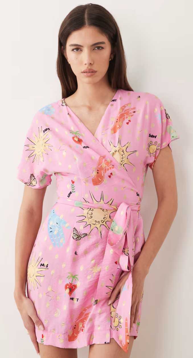 Woman wearing a pink dress with colorful floral and abstract patterns on a white background