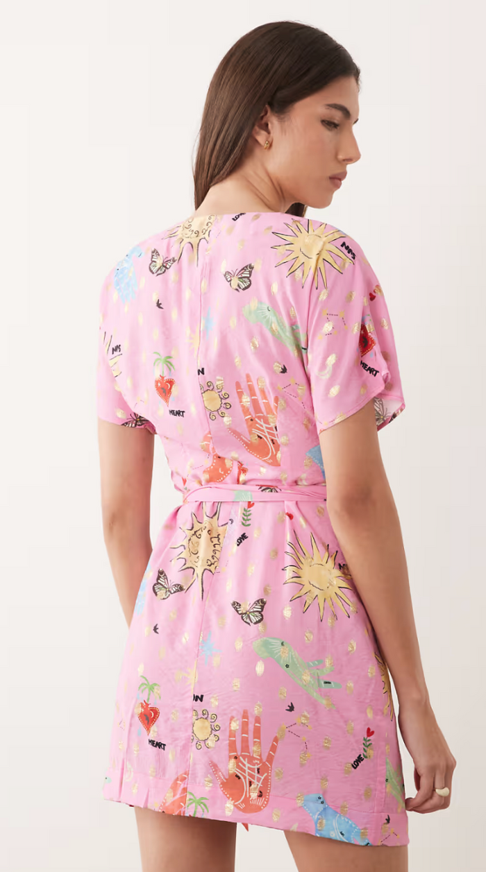 Woman wearing a pink dress with colorful patterns on a white background