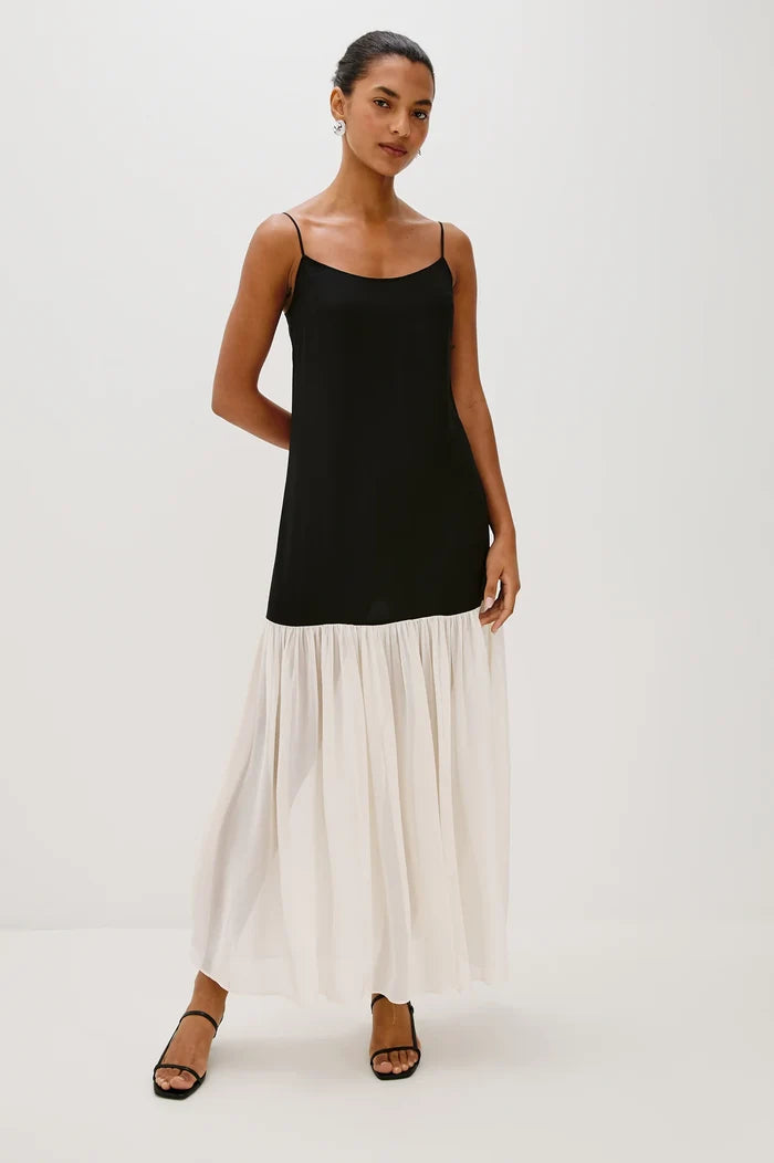 Woman wearing a black top and white pleated skirt on a white background