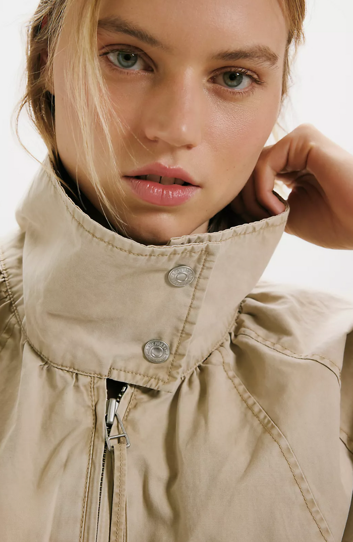 Close-up of a person wearing a beige jacket with a neutral background