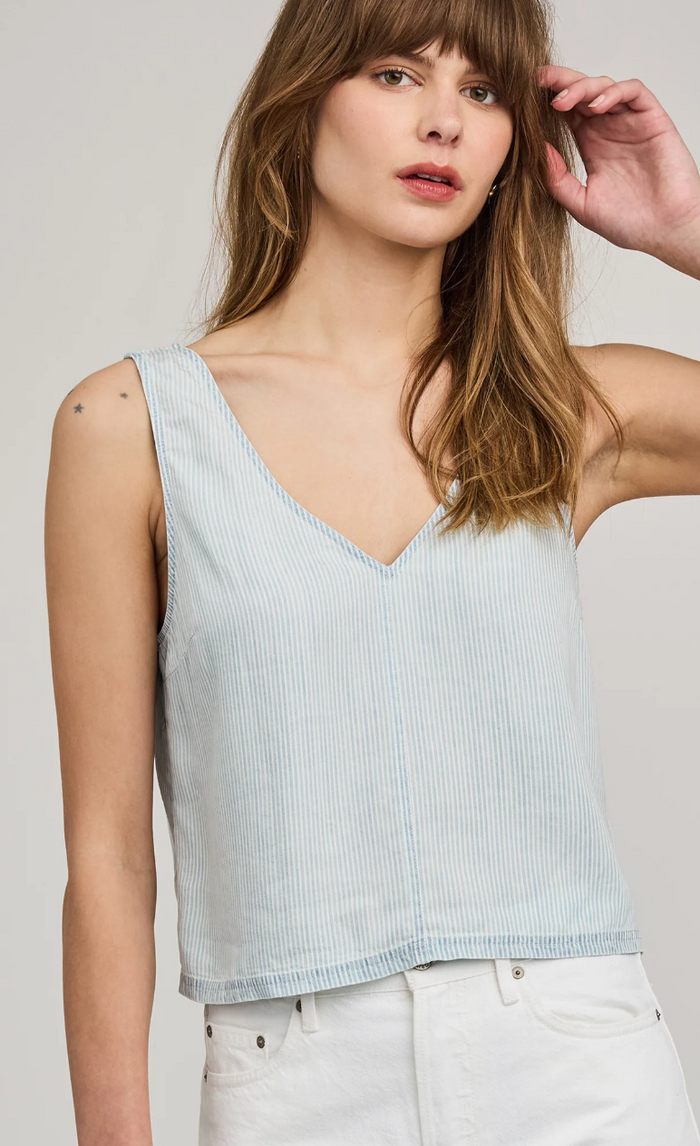 Woman wearing a light blue striped tank top against a plain background