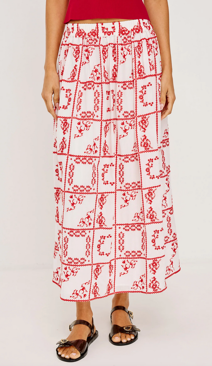 Person wearing a red and white patterned skirt on a plain background