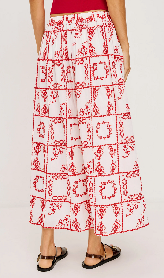 White skirt with red geometric pattern worn by a person on a white background