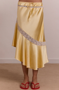 Yellow satin skirt with lace trim worn by a person on a beige background