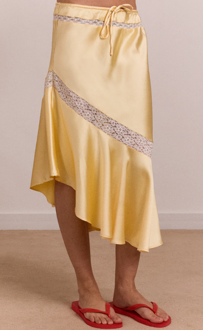 Yellow satin skirt with decorative trim on a neutral background