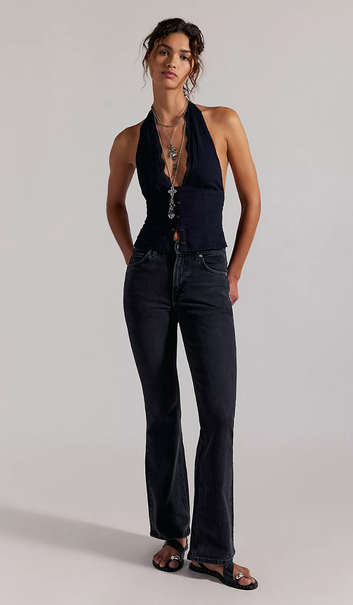 Woman wearing a black halter top and dark horizon pants on a plain background