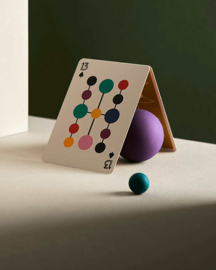 Playing card with colorful design on a table with a purple ball and blue sphere.