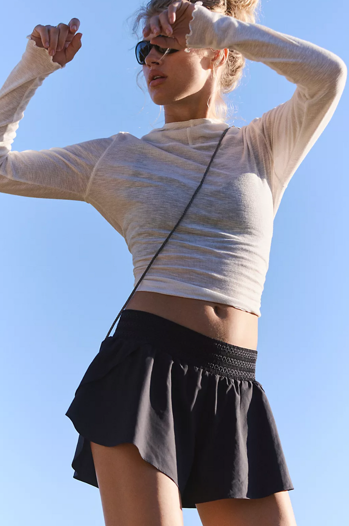 Woman in black shorts athletic wear with a clear blue sky background