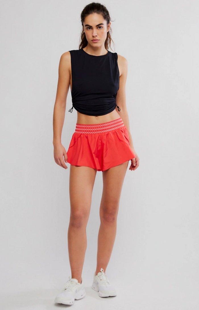 Woman wearing a black sleeveless top and Free People Element shorts in Electric Sunset on a white background