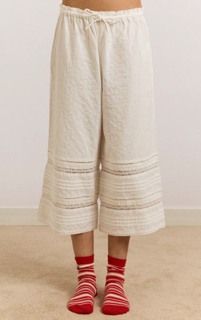 White wide-leg pants worn by a person on a beige carpet with a white wall background