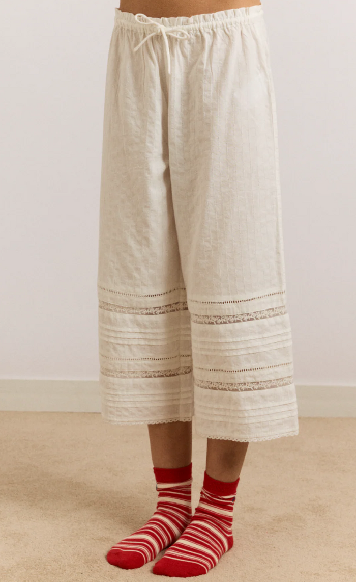 Beige wide-leg pants worn by a person with red striped socks on a beige floor.