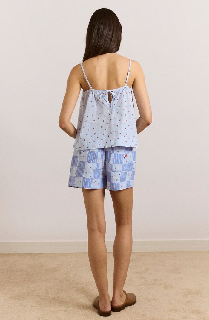 Woman wearing a light blue patterned top and shorts set on a plain background