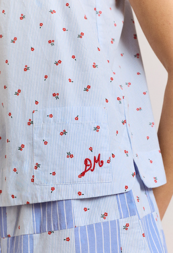 Light blue shirt with red floral pattern and 'DM' logo, worn by a person.