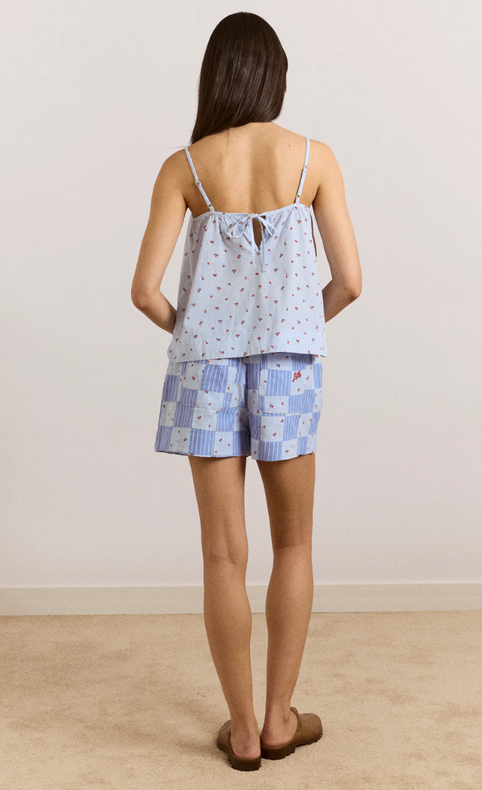 Woman wearing a blue patterned top and shorts set on a plain background