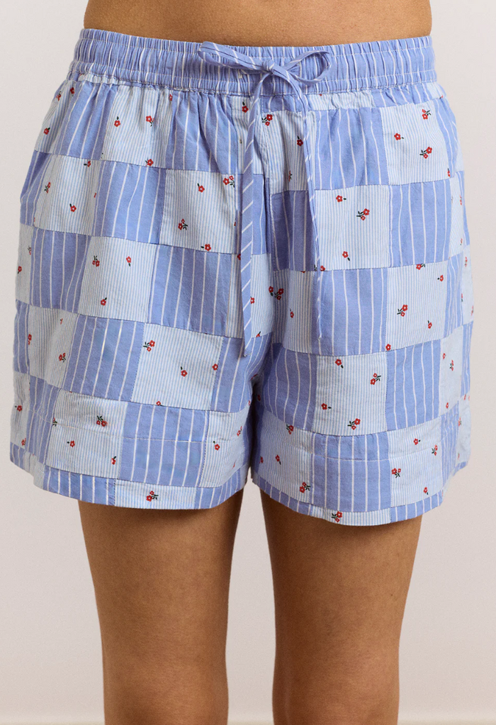 Blue checkered shorts with small red patterns on a plain background