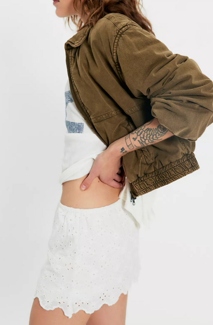Person wearing a green jacket over a Free People Eyes on You Skort Ivory with lace details on a plain background