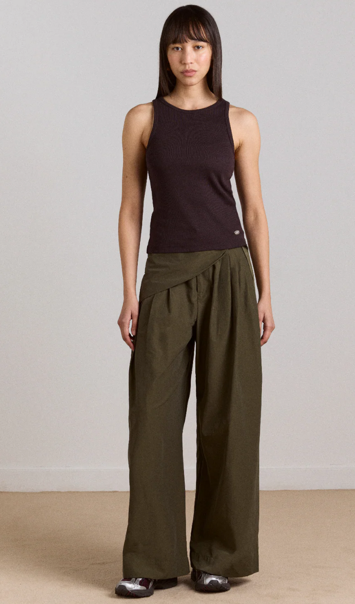 Woman wearing a black sleeveless top and Khaki wide-leg pants on a plain background