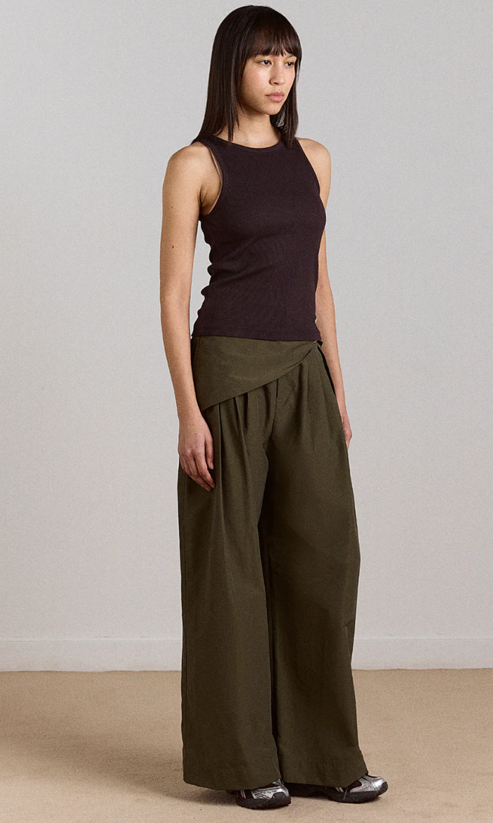Woman wearing a black sleeveless top and okhaki wide-leg pants against a plain background