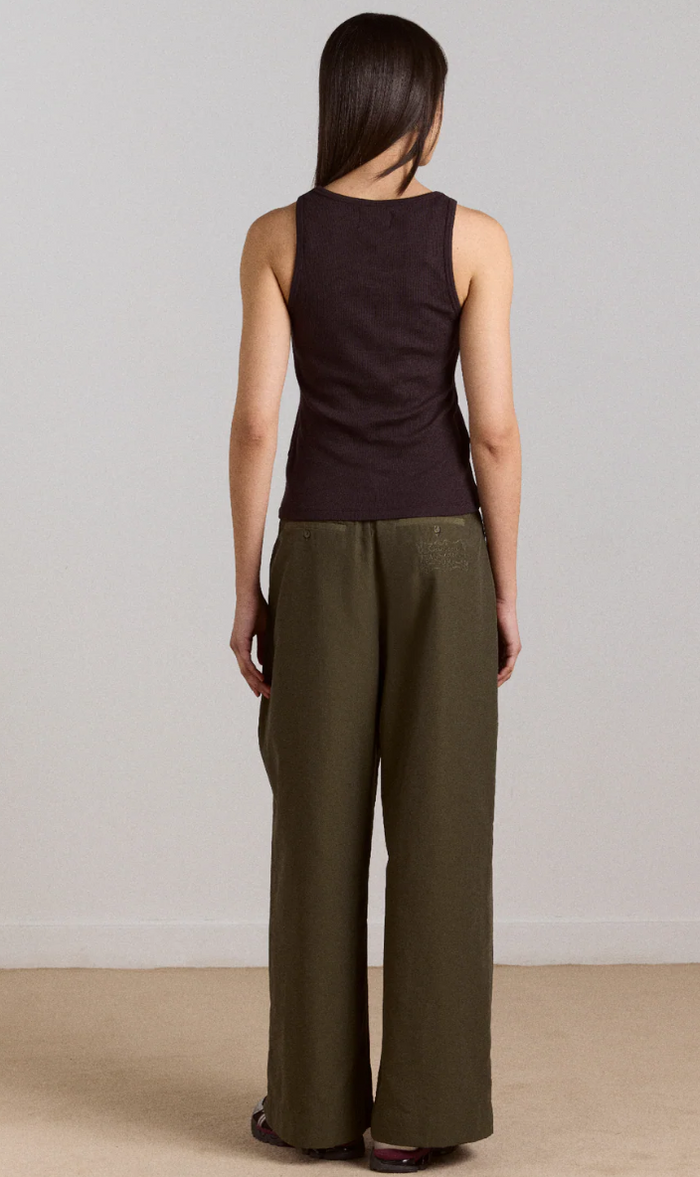 Woman wearing a sleeveless brown top and wide-leg khaki pants against a plain background