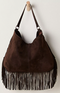 Free People Finn Fringe Shoulder Bag in Espresso with fringes on a wooden hook against a white background
