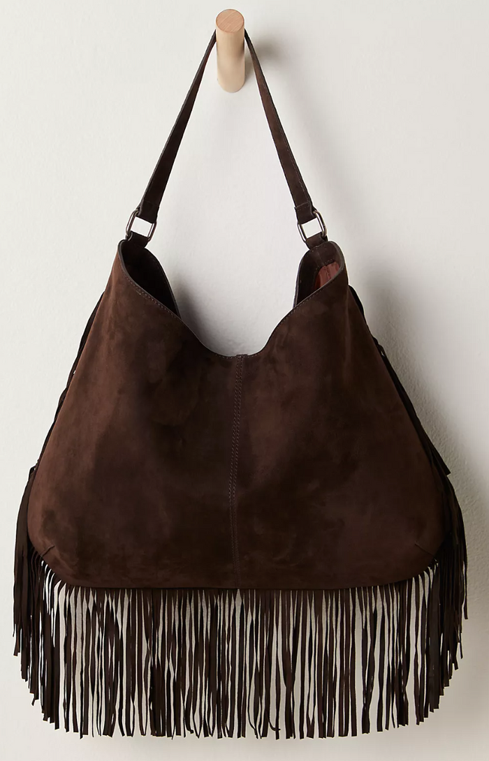 Free People Finn Fringe Shoulder Bag in Espresso with fringes on a wooden hook against a white background