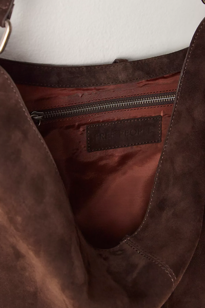 Close-up of a brown leather bag with a visible brand label.
