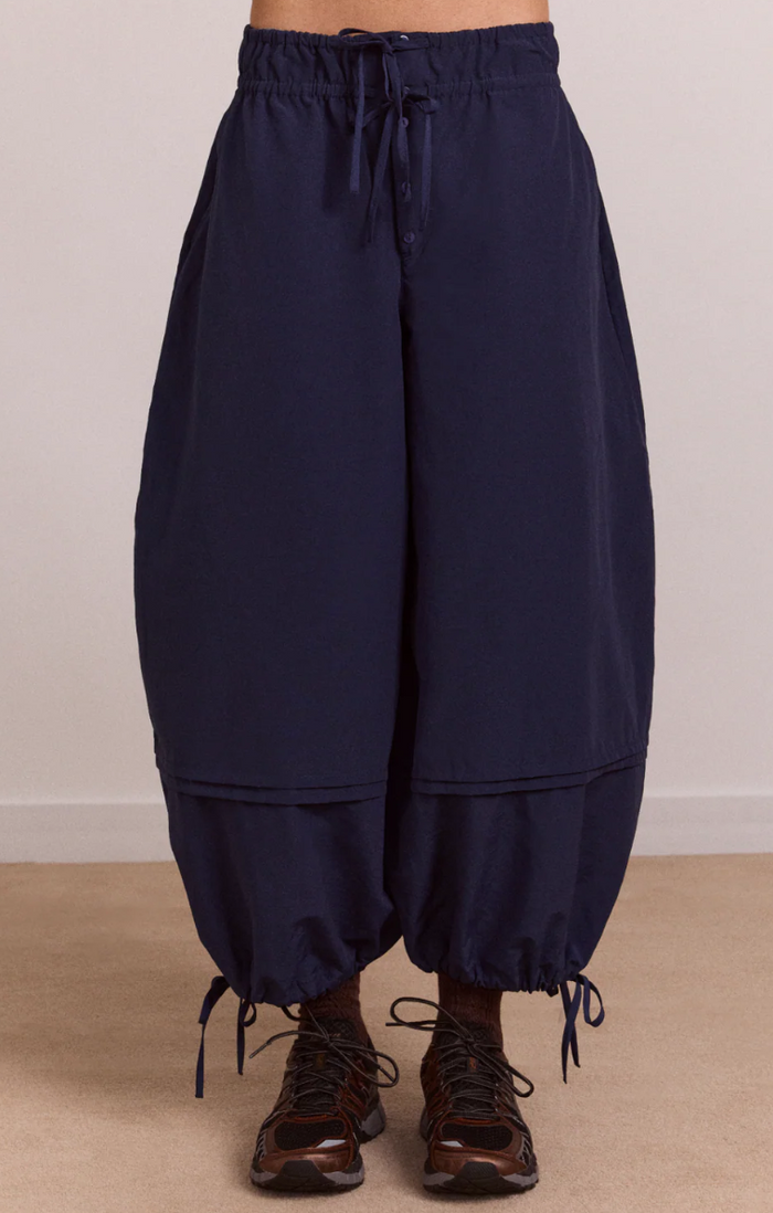 Navy blue wide-leg pants with drawstring waist on a beige background