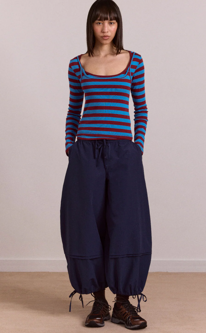 Person wearing a blue and red striped top with navy wide-leg pants on a plain background