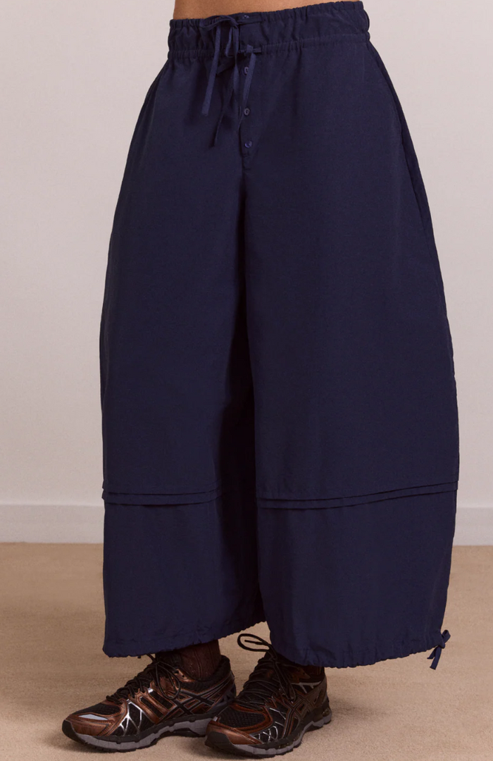 Navy blue wide-leg pants worn by a person on a beige background