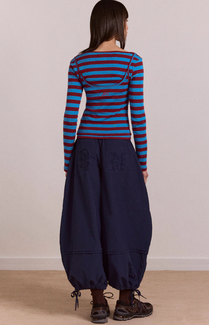 Person wearing a blue and red striped long-sleeve top with navy blue wide-leg pants against a plain background.