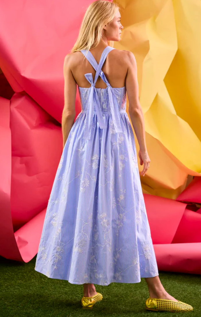 Woman in a light blue dress standing against colorful abstract background