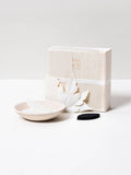 Paper incense leaves, small dish, and black mat on a white surface with a branded box.