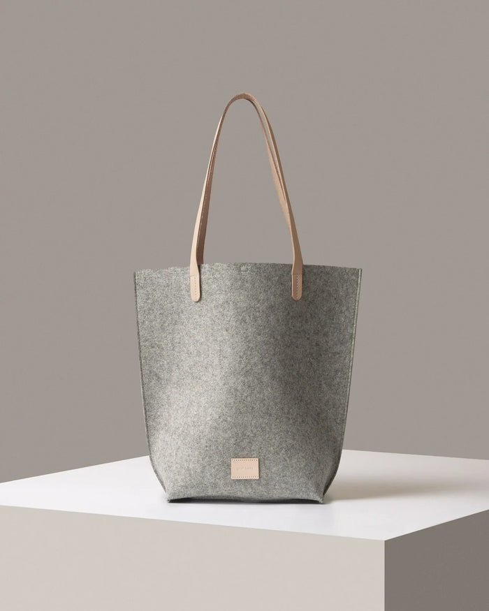 Gray tote bag with beige handle on a neutral background