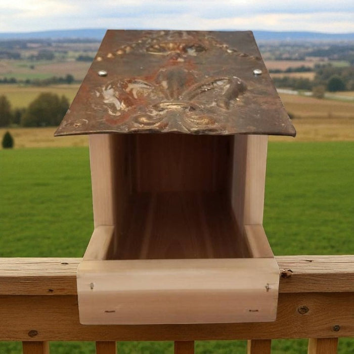 Wooden birdhouse with decorative top against a green landscape