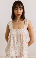 Woman wearing a floral sleeveless top against a plain background